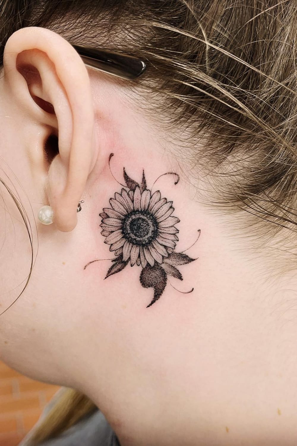 Small sunflower tattoo behind ear