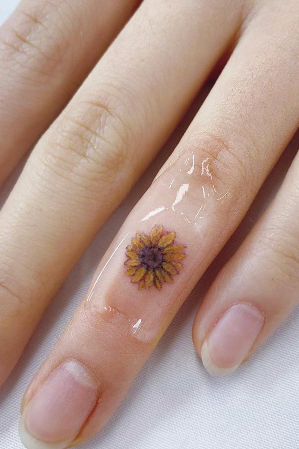 Small sunflower tattoo on finger