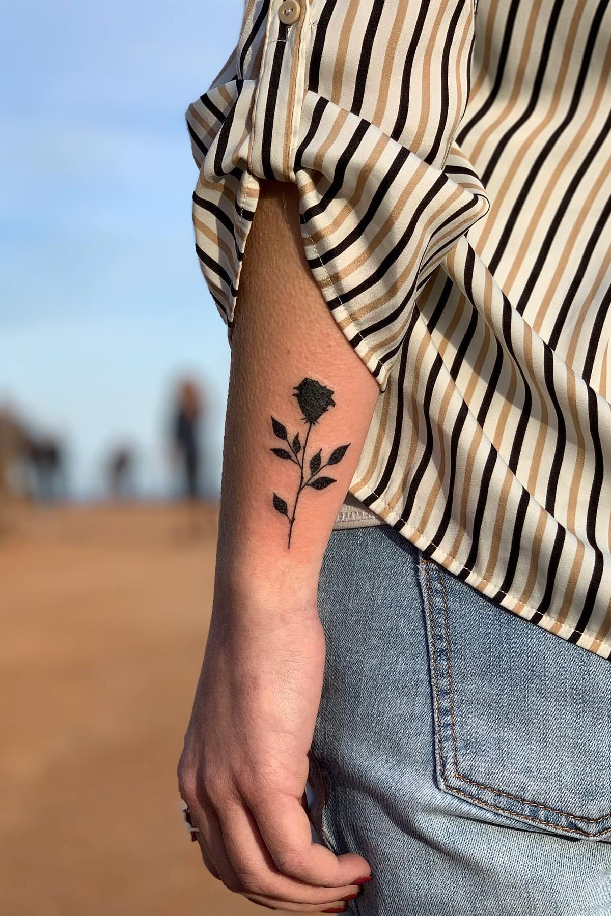 Small black rose tattoo on arm