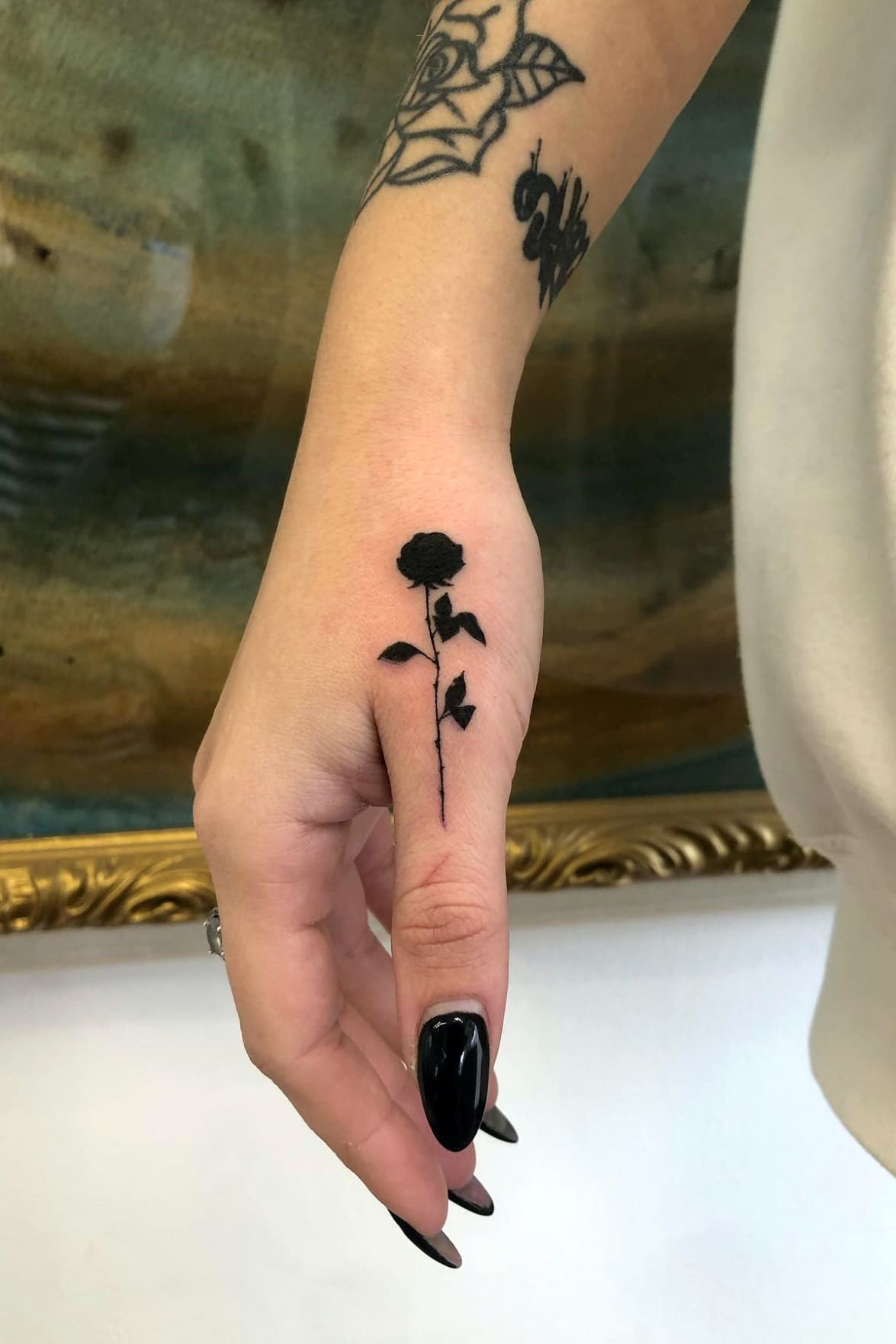 Small black rose tattoo on finger