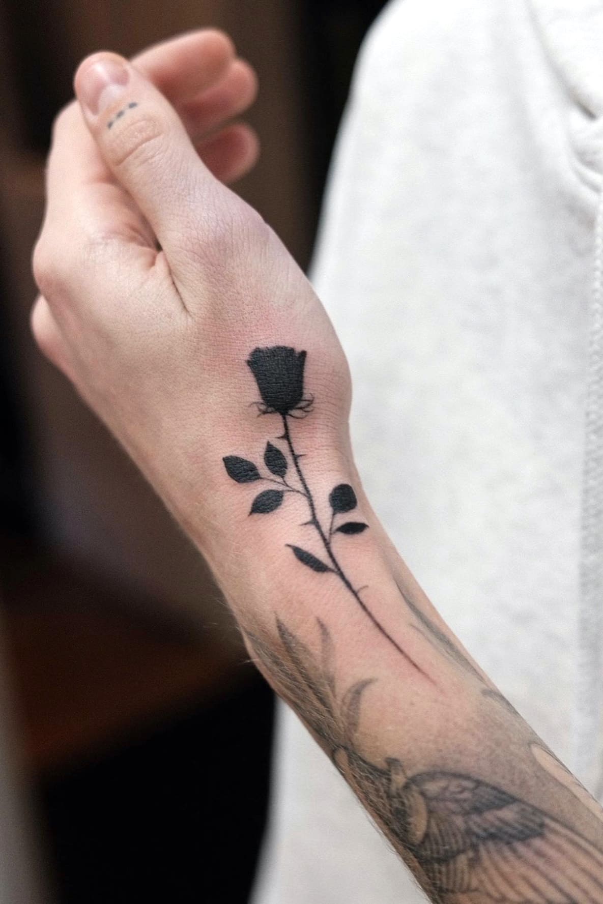 Small black rose tattoo on hand
