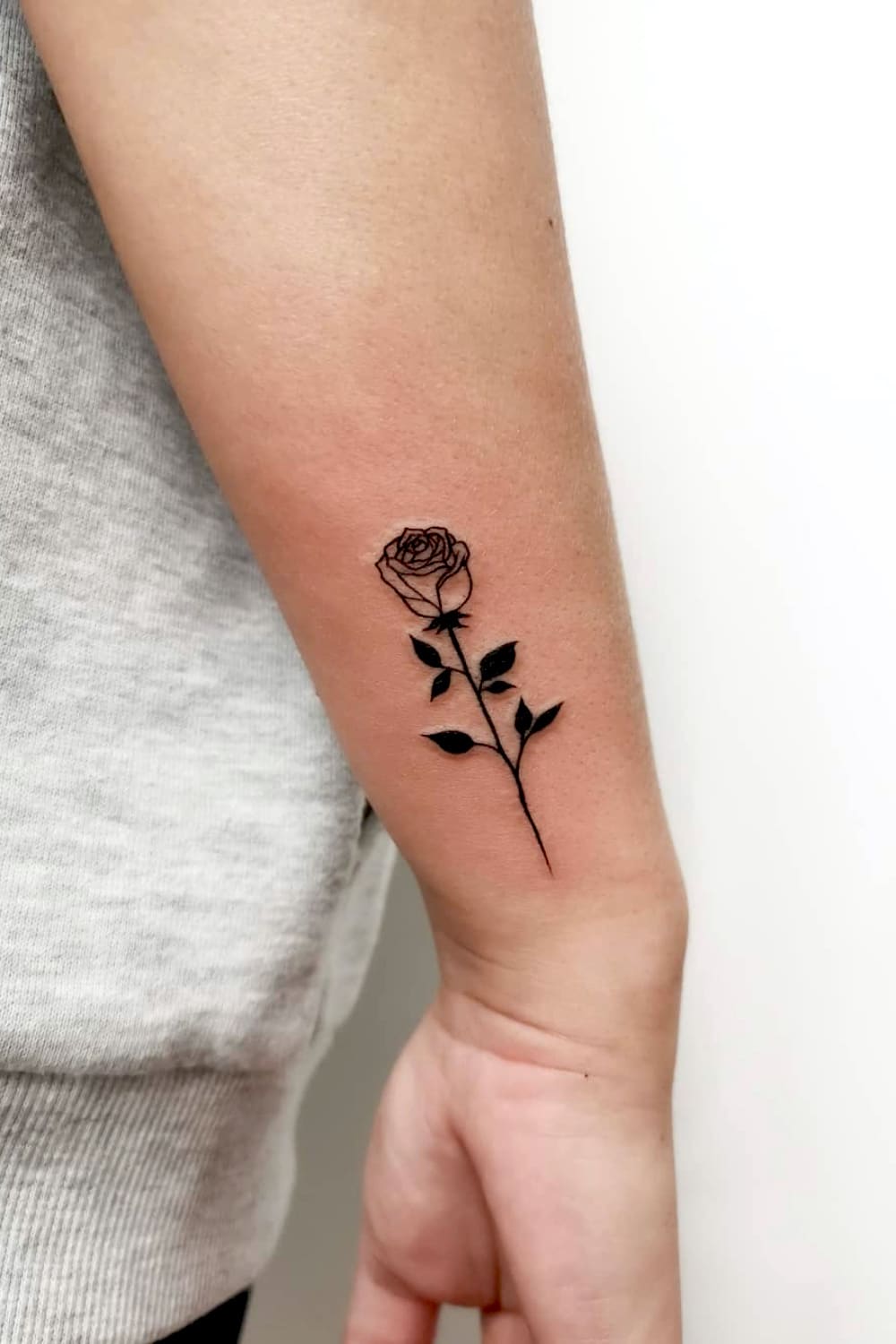 Striking small black rose tattoo